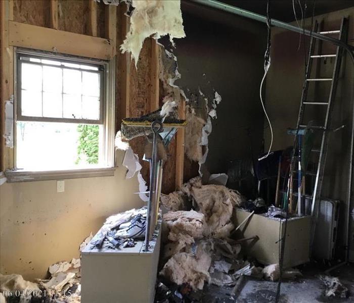 A garage with fire damaged causing missing drywall in a pile