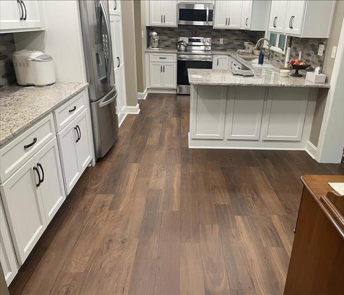 LVP installed in a kitchen with white cabinets and dark brown flooring